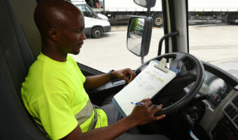 Ein Mann sitzt in einem Lastwagen und studiert seinen Einsatzplan.