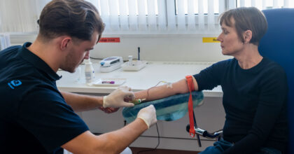 Ein Mann nimmt einer Patientin Blut ab.